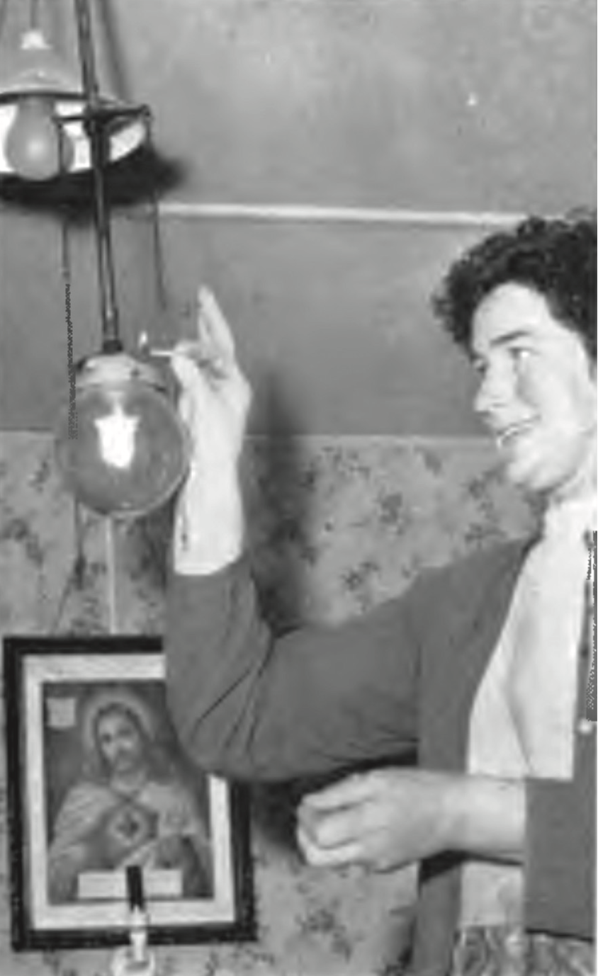 Figure 8: Mrs Nellie Long of Cahirfelane lighting a gas lamp, with a Sacred Heart lamp in the background, Prospect January 1966 (Courtesy of the ESB Archive).
